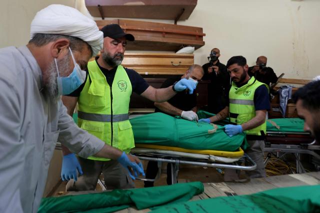 A Shia Muslim sheikh (L) helps during the wrapping of the bodies in shrouds before the burial of nine people killed the day before in an Israeli airstrike on the southern Lebanese village of Jibshit, during their funeral in the city of Sidon on May 10, 2026. Israel carried out strikes across Lebanon on May 9, 2026, killing at least nine people in the south according to authorities, with raids also targeting a highway not far from Beirut outside of Hezbollah's traditional strongholds. Lebanon was drawn into the Middle East war on March 2 when Tehran-backed militant group Hezbollah launched attacks on Israel to avenge the killing of the Iranian leader. Israel has responded with broad strikes across Lebanon and a ground offencive. (Photo by MAHMOUD ZAYYAT / AFP)