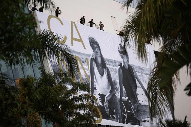 Workers hang the official poster of the 78th Cannes Film Festival on the facade of the Palais des Festivals in Cannes, south-eastern France on May 10, 2026. The Cannes Film festival will take place from May 12 to May 23, 2026. (Photo by Valery HACHE / AFP)