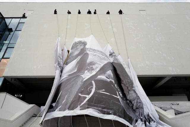 Workers hang the official poster of the 78th Cannes Film Festival on the facade of the Palais des Festivals in Cannes, south-eastern France on May 10, 2026. The Cannes Film festival will take place from May 12 to May 23, 2026. (Photo by Valery HACHE / AFP)