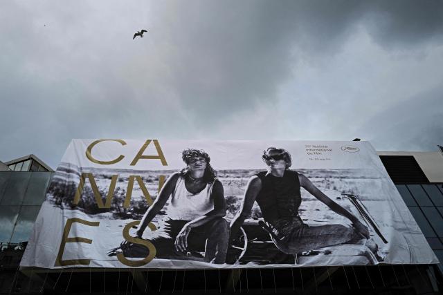 A seagull flies past the official poster of the 78th Cannes Film Festival during its hanging on the facade of the Palais des Festivals in Cannes, south-eastern France on May 10, 2026. The Cannes Film festival will take place from May 12 to May 23, 2026. (Photo by Valery HACHE / AFP)