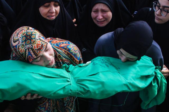 Two Lebanese women holds their heads against a shrouded body, of one of nine people killed the day before in an Israeli airstrike on the southern Lebanese village of Jibshit, during their funeral in the city of Sidon on May 10, 2026. Israel carried out strikes across Lebanon on May 9, 2026, killing at least nine people, in the south according to authorities, with raids also targeting a highway not far from Beirut outside of Hezbollah's traditional strongholds. Lebanon was drawn into the Middle East war on March 2 when Tehran-backed militant group Hezbollah launched attacks on Israel to avenge the killing of the Iranian leader. Israel has responded with broad strikes across Lebanon and a ground offencive. (Photo by Mahmoud ZAYYAT / AFP)