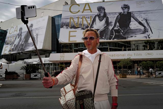 A bystander takes a 'selfie' in front of the official poster of the 78th Cannes Film Festival on the facade of the Palais des Festivals in Cannes, south-eastern France on May 10, 2026. The Cannes Film festival is scheduled to take place from May 12 to May 23. (Photo by Valery HACHE / AFP)