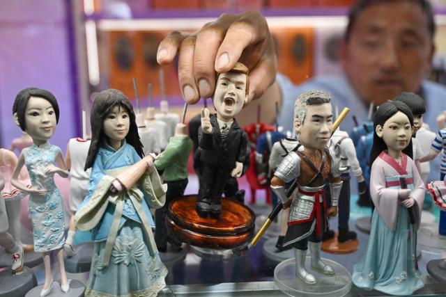 A salesperson takes a plastic figure depicting US President Donald Trump displayed in a showcase for sale in a store in Beijing on May 10, 2026. Trump is due to visit China on May 14-15 where he is expected to meet with China's President Xi after delaying an earlier summit due to the Middle East war. (Photo by Pedro Pardo / AFP)