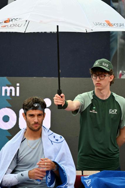TOPSHOT - Italy's Lorenzo Musetti waits for referee's decision as it rains before his men's singles match against Argentina's Francisco Cerundolo at the ATP Rome Open tennis tournament at Foro Italico in Rome on May 10, 2026. (Photo by Alberto PIZZOLI / AFP)