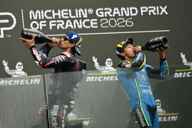 TOPSHOT - Aprilia Racing's Spanish rider Jorge Martin (L) celebrates on the podium next to third placed Trackhouse Racing MotoGP Team's Japanese rider Ai Ogura (R) after winning the Moto GP Grand Prix of France at Le Mans, northwestern France, on May 10, 2026. (Photo by Loic VENANCE / AFP)