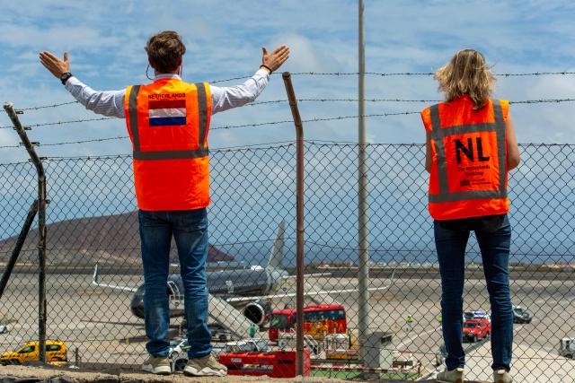 Dutch embassy representatives look on as passengers board a plane bound for the Netherlands at the Tenerife Sur-Reina Sofia airport after the passenters were evacuated from the Dutch flagged hantavirus-stricken cruise ship MV Hondius on the island of Tenerife in Spain's Canary Islands on May 10, 2026. Repatriation flights for the nearly 150 passengers onboard the ship hit by a deadly hantavirus outbreak got underway as passengers and some crew members were transferred to shore on smaller vessels then by bus to the airport and then flown home after weeks at sea. (Photo by Antonio Sempere / AFP)