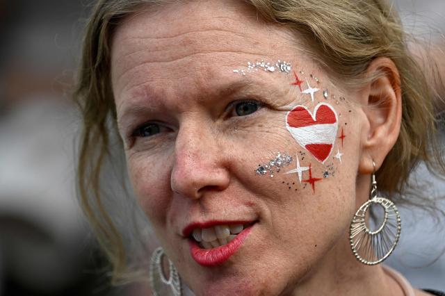 A woman with face painted in the colors of the Austrian flag attends the opening ceremony of the Eurovision Song Contest 2026 at the City Hall Square in Vienna, Austria on May 10, 2026. The event is the official starting point of Eurovision week in Vienna. The city will host the two semi-finals on May 12 and May 14 and the final on May 16, 2026. (Photo by Tobias SCHWARZ / AFP)