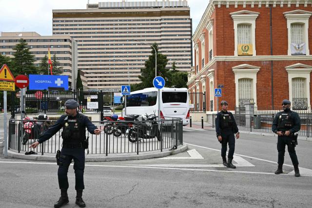 Police stand guard as the convoy of Spanish passengers that were evacuated from the Dutch flagged hantavirus-stricken cruise ship MV Hondius arrives to the Gomez Ulla Defense Hospital in Madrid. on May 10, 2026. Repatriation flights for the nearly 150 passengers onboard the ship hit by a deadly hantavirus outbreak got underway as passengers and some crew members were transferred to shore on smaller vessels then by bus to the airport and then flown home after weeks at sea. (Photo by Javier SORIANO / AFP)