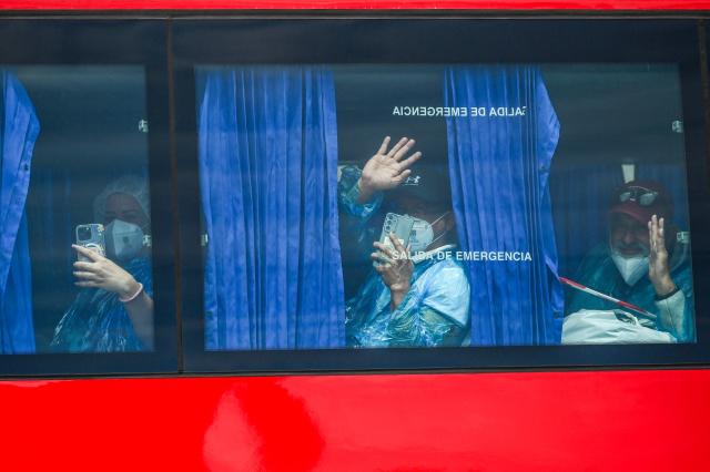 Passengers evacuated from the Dutch flagged hantavirus-stricken cruise ship MV Hondius wave aboard a military bus after being transferred by boat to the industrial port of Granadilla de Abona on the island of Tenerife in Spain's Canary Islands on May 10, 2026. Repatriation flights for the nearly 150 passengers onboard the ship hit by a deadly hantavirus outbreak began as passengers were transferred to shore on smaller vessels then by bus to the airport to be flown home after weeks at sea. (Photo by JORGE GUERRERO / AFP)