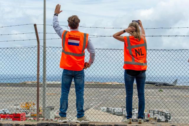Representatives from the Netherlands embassy wave as a plane bound for the Netherlands carrying passengers evacuated from the Dutch flagged hantavirus-stricken cruise ship MV Hondius prepares to take off from the Tenerife Sur-Reina Sofia airport on the island of Tenerife in Spain's Canary Islands on May 10, 2026. Repatriation flights for the nearly 150 passengers onboard the ship hit by a deadly hantavirus outbreak got underway as passengers and some crew members were transferred to shore on smaller vessels then by bus to the airport and then flown home after weeks at sea. (Photo by Antonio Sempere / AFP)