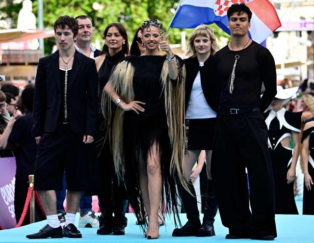 Darina Nikolaeva Yotova (C), aka Dara and representing Bulgaria with the song 'Bangaranga', poses for photographers on the turquoise carpet for the opening ceremony of the Eurovision Song Contest 2026 at the City Hall Square in Vienna, Austria on May 10, 2026. The event is the official starting point of Eurovision week in Vienna. The city will host the two semi-finals on May 12 and May 14 and the final on May 16, 2026. (Photo by Tobias SCHWARZ / AFP)