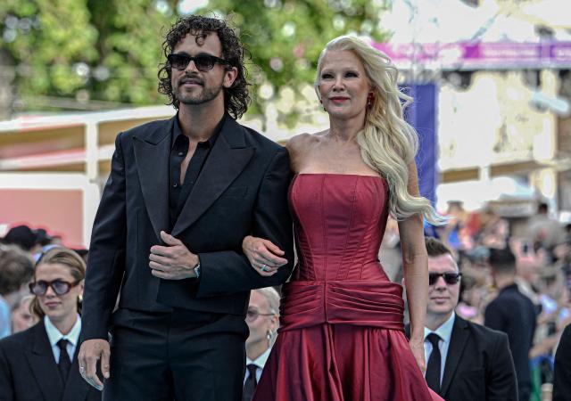 Finnish singers Linda Lampenius (R) and Pete Parkkonen, representing Finland with the song 'Liekinheitin', pose for photographers on the turquoise carpet for the opening ceremony of the Eurovision Song Contest 2026 at the City Hall Square in Vienna, Austria on May 10, 2026. The event is the official starting point of Eurovision week in Vienna. The city will host the two semi-finals on May 12 and May 14 and the final on May 16, 2026. (Photo by Tobias SCHWARZ / AFP)