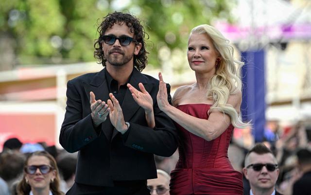 Finnish singers Linda Lampenius (R) and Pete Parkkonen, representing Finland with the song 'Liekinheitin', pose for photographers on the turquoise carpet for the opening ceremony of the Eurovision Song Contest 2026 at the City Hall Square in Vienna, Austria on May 10, 2026. The event is the official starting point of Eurovision week in Vienna. The city will host the two semi-finals on May 12 and May 14 and the final on May 16, 2026. (Photo by Tobias SCHWARZ / AFP)