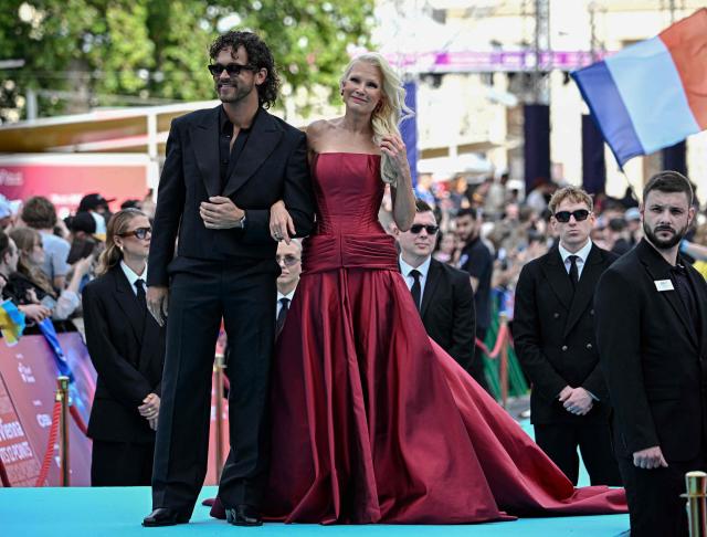 Finnish singers Linda Lampenius (R) and Pete Parkkonen, representing Finland with the song 'Liekinheitin', pose for photographers on the turquoise carpet for the opening ceremony of the Eurovision Song Contest 2026 at the City Hall Square in Vienna, Austria on May 10, 2026. The event is the official starting point of Eurovision week in Vienna. The city will host the two semi-finals on May 12 and May 14 and the final on May 16, 2026. (Photo by Tobias SCHWARZ / AFP)