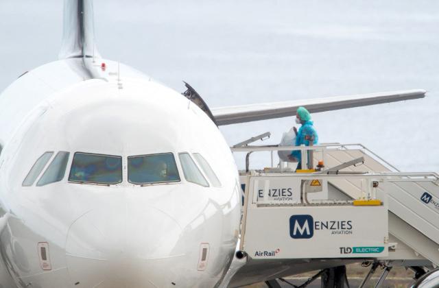 A British citizen boards a plane bound for the UK carrying passengers evacuated from the Dutch flagged hantavirus-stricken cruise ship MV Hondius at the Tenerife Sur-Reina Sofia airport on the island of Tenerife in Spain's Canary Islands on May 10, 2026. Repatriation flights for the nearly 150 passengers onboard the ship hit by a deadly hantavirus outbreak got underway as passengers and some crew members were transferred to shore on smaller vessels then by bus to the airport and then flown home after weeks at sea. (Photo by Antonio Sempere / AFP)