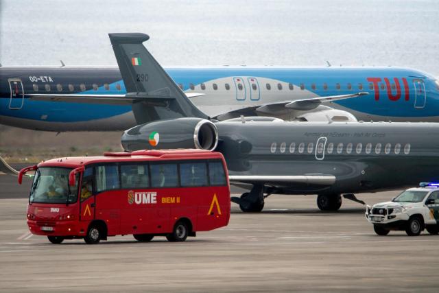 An Irish Air Corps plane (C) is pictured next to another plane, a Spain's Emergency Military Unit (UME) and a Spain's Guardia Civil vehicle at the Tenerife Sur-Reina Sofia airport on the island of Tenerife in Spain's Canary Islands on May 10, 2026. Repatriation flights for the nearly 150 passengers onboard the ship hit by a deadly hantavirus outbreak got underway as passengers and some crew members were transferred to shore on smaller vessels then by bus to the airport and then flown home after weeks at sea. (Photo by Antonio Sempere / AFP)