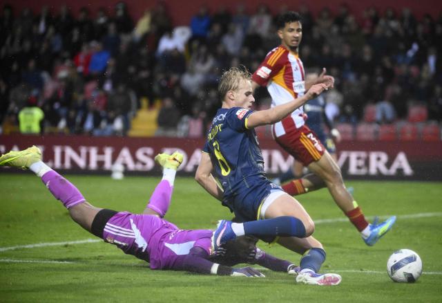 FC Porto's Danish midfielder #08 Victor Froholdt challenges AVS' Brazilian goalkeeper #01 Adriel during the Portuguese League football match between AVS Futebol SAD and FC Porto at at CD Aves stadium in Vila das Aves on May 10, 2026. (Photo by Miguel RIOPA / AFP)