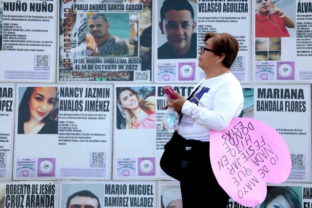 A mother searching for her missing child holds a sign reading "May 10, nothing to celebrate, son, where are you?" as posters of missing people are displayed in the background during a protest on Mother's Day, in Guadalajara, Jalisco state, Mexico, on May 10, 2026. (Photo by ULISES RUIZ / AFP)