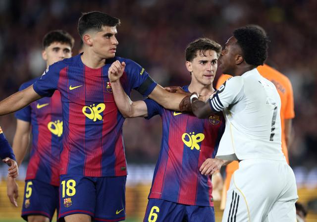 Real Madrid's Brazilian forward #07 Vinicius Junior clashes with Barcelona's players during the Spanish league football match between FC Barcelona and Real Madrid CF at Camp Nou Stadium in Barcelona on May 10, 2026. (Photo by Josep LAGO / AFP)