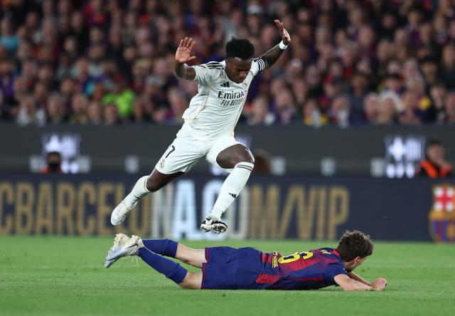 Real Madrid's Brazilian forward #07 Vinicius Junior jumps past Barcelona's Spanish midfielder #06 Pablo Gavi during the Spanish league football match between FC Barcelona and Real Madrid CF at Camp Nou Stadium in Barcelona on May 10, 2026. (Photo by Josep LAGO / AFP)