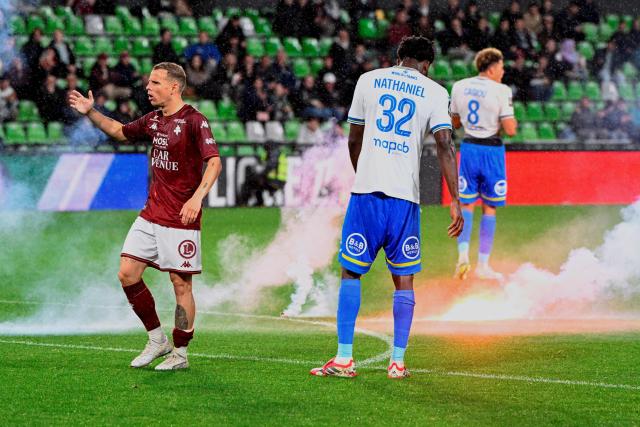 Metz' French midfielder #10 Gauthier Hein (L) reacts as Metz' supporters light flares and throw them onto the pitch during the French L1 football match between FC Metz and FC Lorient at the Stade Saint-Symphorien in Longeville-les-Metz, eastern France on May 10, 2026. (Photo by Jean-Christophe VERHAEGEN / AFP)