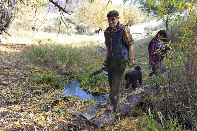 Victor Diaz, identified by health authorities as patient zero in the 2018-2019 hantavirus outbreak that killed 11 people, including his wife, and his daughter Isabel (R) cross a stream at his farm in the La Rinconada area near Epuyen, Chubut province, Argentina, on May 9, 2026. (Photo by JUAN MABROMATA / AFP)