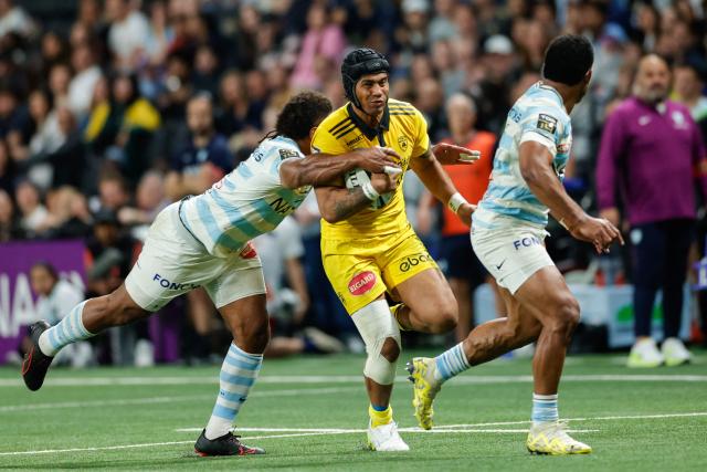 La Rochelle's Australian centre Ulupano Seuteni (C) is tackled as he runs with the ball during the French Top14 rugby union match between Racing 92 and Stade Rochelais (La Rochelle) at the Paris La Defense Arena in Nanterre, on the outskirts of Paris on May 10, 2026. (Photo by GEOFFROY VAN DER HASSELT / AFP)