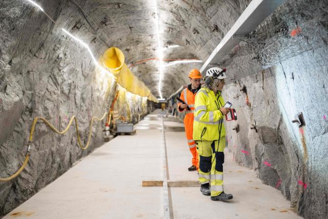 ETH Zurich Master students Alba Zappone (R) and Alessandro Profeta (rear) examine the cracks in the BedrettoLab tunnel, a unique underground research facility operated by the Federal Institute of Technology Zurich (ETH Zurich) located 1500m beneath the Swiss Alps within a 5.2 km tunnel near Bedretto, on April 29, 2026. Researchers have made the ground shake triggering thousands of tiny earthquakes in a monitored setting, as they seek to discover seismicity insights that can reduce risks. (Photo by Ennio LEANZA / AFP)