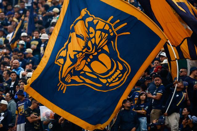 Fans of Pumas wave a flag before the Liga MX Clausura quarter-finals second leg football match between Pumas and America at the Olimpico Universitario stadium in Mexico City on May 10, 2026. (Photo by Rodrigo Oropeza / AFP)