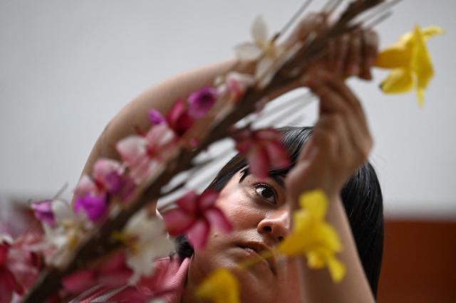 A woman decorates a palm leaf with flowers before the annual Brotherhood of Flowers and Palms festival procession in the indigenous town of Panchimalco, El Salvador, on May 10, 2026. This year, the traditional religious and cultural festivity is being held following El Salvador’s first inscription on UNESCO's Representative List of the Intangible Cultural Heritage of Humanity announced on December 10, 2025. (Photo by MARVIN RECINOS / AFP)