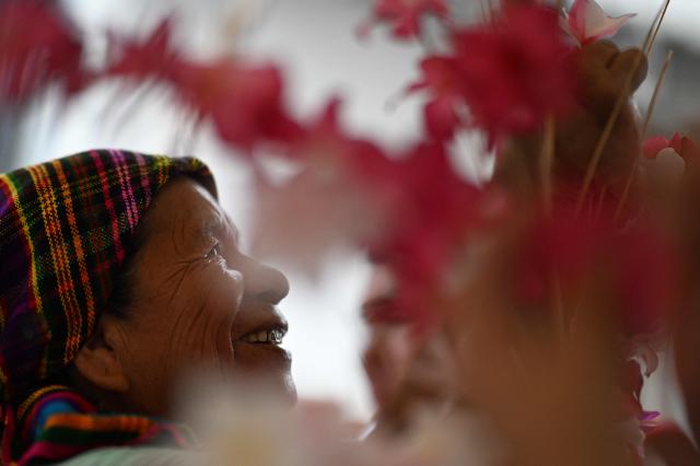 A woman decorates a palm leaf with flowers before the annual Brotherhood of Flowers and Palms festival procession in the indigenous town of Panchimalco, El Salvador, on May 10, 2026. This year, the traditional religious and cultural festivity is being held following El Salvador’s first inscription on UNESCO's Representative List of the Intangible Cultural Heritage of Humanity announced on December 10, 2025. (Photo by MARVIN RECINOS / AFP)
