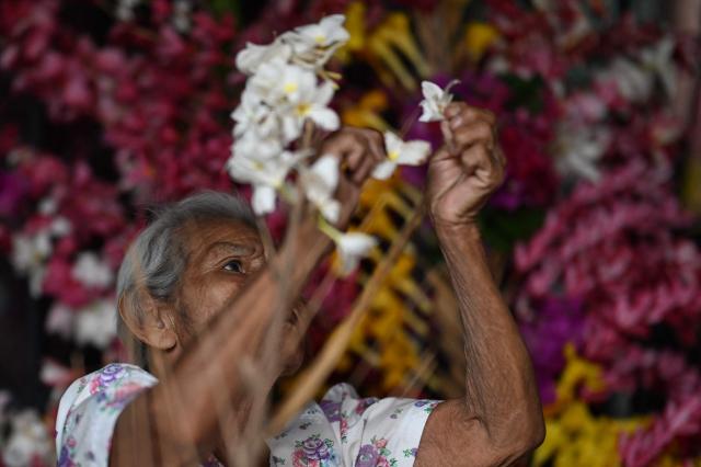 A woman decorates a palm leaf with flowers before the annual Brotherhood of Flowers and Palms festival procession in the indigenous town of Panchimalco, El Salvador, on May 10, 2026. This year, the traditional religious and cultural festivity is being held following El Salvador’s first inscription on UNESCO's Representative List of the Intangible Cultural Heritage of Humanity announced on December 10, 2025. (Photo by MARVIN RECINOS / AFP)