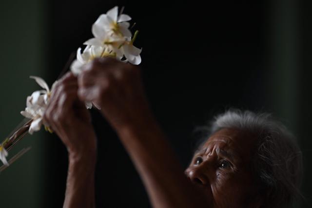 A woman decorates a palm leaf with flowers before the annual Brotherhood of Flowers and Palms festival procession in the indigenous town of Panchimalco, El Salvador, on May 10, 2026. This year, the traditional religious and cultural festivity is being held following El Salvador’s first inscription on UNESCO's Representative List of the Intangible Cultural Heritage of Humanity announced on December 10, 2025. (Photo by MARVIN RECINOS / AFP)