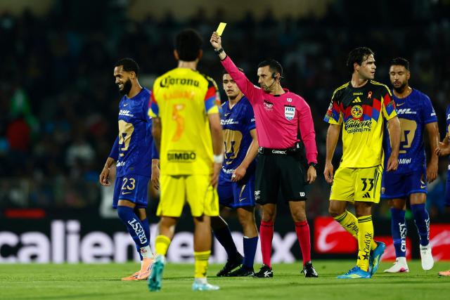 Mexican referee Cesar Ramos shows a yellow card to Pumas' Brazilian forward #23 Juninho Vieira during the Liga MX Clausura quarter-final second leg football match between Pumas and America at Olimpico Universitario stadium in Mexico City on May 10, 2026. (Photo by Rodrigo Oropeza / AFP)