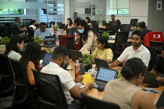 This photograph taken on April 9, 2026 shows Go Digit Insurance employees working at their office in Bengaluru. Adarsh Agarwal, appointed actuary at Go Digit, said his company has covered more than 50,000 people since it began working on parametric insurance two years ago. While still a "niche product", he said demand has increased. There is now "more knowledge and more curiosity," he told AFP, and his firm has offered both heat and air-quality parametric schemes. (Photo by Idrees MOHAMMED / AFP) / To go with 'INDIA-CLIMATE-INSURANCE, FOCUS' by Uzmi ATHAR with Aishwarya KUMAR