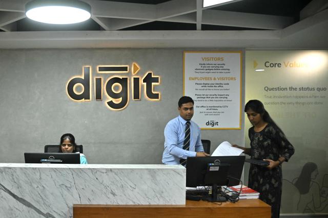 This photograph taken on April 9, 2026 shows Go Digit Insurance employees working behind the reception desk at their office in Bengaluru. Adarsh Agarwal, appointed actuary at Go Digit, said his company has covered more than 50,000 people since it began working on parametric insurance two years ago. While still a "niche product", he said demand has increased. There is now "more knowledge and more curiosity," he told AFP, and his firm has offered both heat and air-quality parametric schemes. (Photo by Idrees MOHAMMED / AFP) / To go with 'INDIA-CLIMATE-INSURANCE, FOCUS' by Uzmi ATHAR with Aishwarya KUMAR