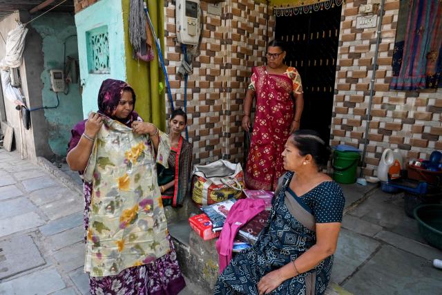 This photograph taken on April 28, 2026 shows Lata Solanki (L), a clothes seller and policyholder of a heat insurance scheme, conducting a door-to-door sales in Ahmedabad. Solanki used to face a devastating choice when India's summer heat hit dangerous levels: risk her health going door-to-door for sales, or lose her income? But now the 42-year-old is part of a insurance scheme that pays out when temperatures hit a threshold, so she can stay home without jeopardising her finances. (Photo by Shammi MEHRA / AFP) / To go with 'INDIA-CLIMATE-INSURANCE, FOCUS' by Uzmi ATHAR with Aishwarya KUMAR