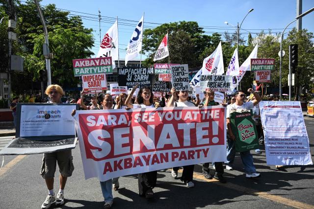 Protesters holding a banner and signs protest in support of the impeachment of Philippine Vice-President Sara Duterte as they march toward the House of Representatives in Quezon City, Metro Manila on May 11, 2026. (Photo by TED ALJIBE / AFP)