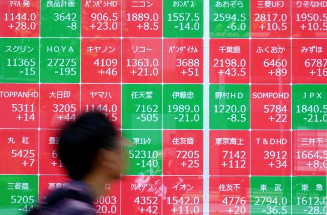 A man walks past an electronic quotation board displaying the Nikkei 225 stock prices on the Tokyo Stock Exchange along a street in Tokyo on May 11, 2026. (Photo by Kazuhiro NOGI / AFP)