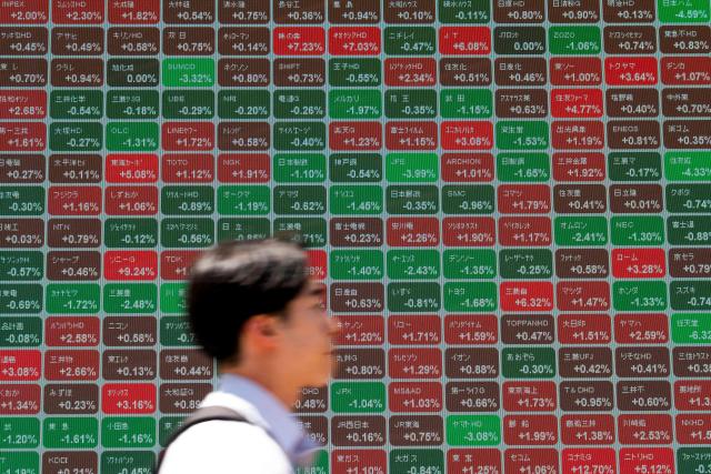 A man walks past an electronic quotation board displaying the Nikkei 225 stock prices on the Tokyo Stock Exchange along a street in Tokyo on May 11, 2026. (Photo by Kazuhiro NOGI / AFP)