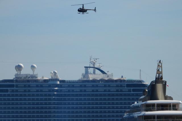 (FILES) An helicopter flies over the MSC Seaview line cruiser during the 72nd edition of the Cannes Film Festival in Cannes, southern France on May 16, 2019. Wealthy customers, congested roads, and stunning scenery: despite growing public criticism, the French Riviera remains a thriving market for helicopter transportation, which is gearing up for the electric aircraft revolution. (Photo by Laurent EMMANUEL / AFP)