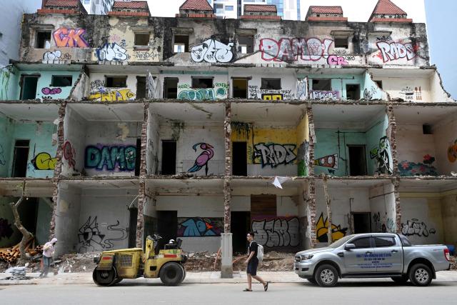 A man walks past a demolition site in Hanoi on May 11, 2026. (Photo by Nhac NGUYEN / AFP)