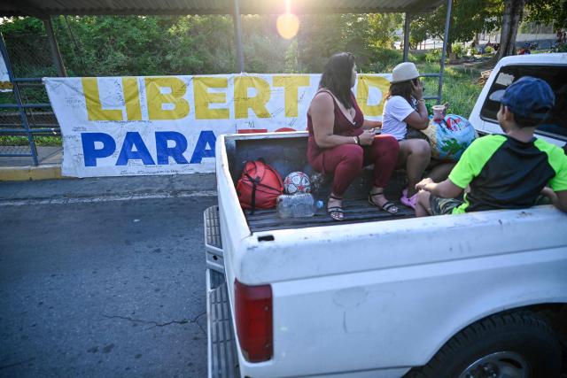 A pickup truck drives past a sign demanding the release of political prisoners outside El Rodeo I prison in Guatire, Miranda state, Venezuela on May 10, 2026. (Photo by Juan BARRETO / AFP)
