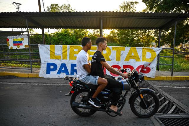 A motorbike drives past a sign demanding the release of political prisoners outside El Rodeo I prison in Guatire, Miranda state, Venezuela on May 10, 2026. (Photo by Juan BARRETO / AFP)