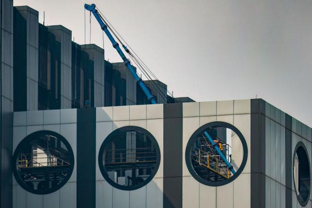 Construction workers complete work on the roof of a building in Jakarta on May 11, 2026. (Photo by BAY ISMOYO / AFP)