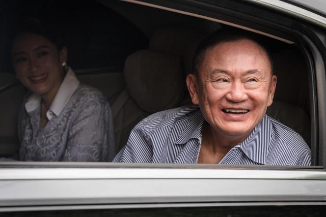 Thailand's former prime minister Thaksin Shinawatra (R) looks on as he arrives at his residency in a car with his daughter Paetongtarn Shinawatra after his release from Klong Prem Central Prison in Bangkok on May 11, 2026. Thailand's former prime minister Thaksin Shinawatra was released early from prison on May 11, raising the prospect of a return to the spotlight for the political heavyweight. (Photo by chanakarn LAOSARAKHAM / AFP)