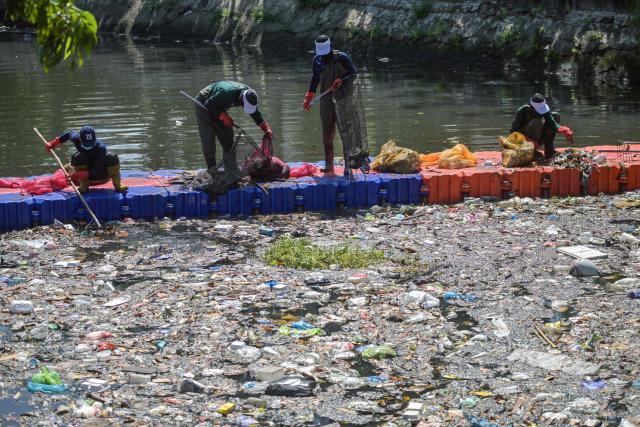 Activists from ECOTON (Ecological Observation and Wetland Conservations) and workers from the city government’s Environmental Agency clean trash from the Kali Tebu River in Surabaya, Indonesia's East Java province, on May 11, 2026. (Photo by JUNI KRISWANTO / AFP)