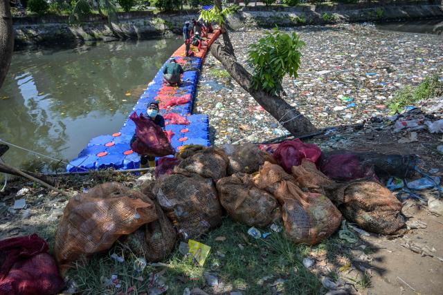 Activists from ECOTON (Ecological Observation and Wetland Conservations) and workers from the city government’s Environmental Agency clean trash from the Kali Tebu River in Surabaya, Indonesia's East Java province, on May 11, 2026. (Photo by JUNI KRISWANTO / AFP)
