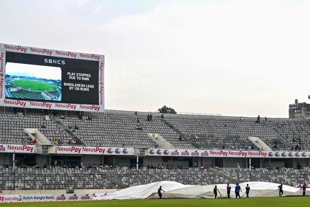 Ground staff cover the field as rain stops the play during the fourth day of the first Test cricket match between Bangladesh and Pakistan at the Sher-e-Bangla National Stadium in Mirpur on May 11, 2026. (Photo by Munir UZ ZAMAN / AFP)