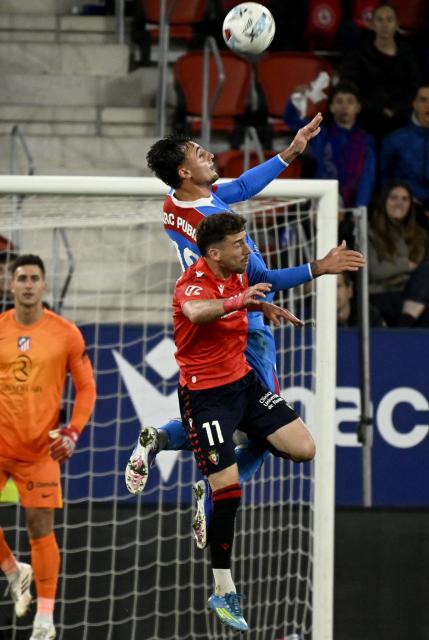 Osasuna's Spanish forward #11 Kike Barja heads the ball with Atletico Madrid's Spanish defender #18 Marc Pubill during the Spanish league football match between CA Osasuna and Club Atletico de Madrid at El Sadar Stadium in Pamplona on May 12, 2026. (Photo by ANDER GILLENEA / AFP)